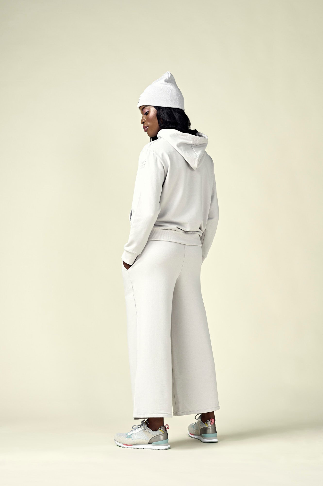 Back view of woman in oyster coloured hoodie and matching wide leg pants and matching beanie. 