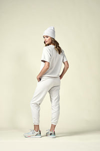 Back view of woman in oyster coloured short sleeve sweatshirt and matching joggers and matching beanie.