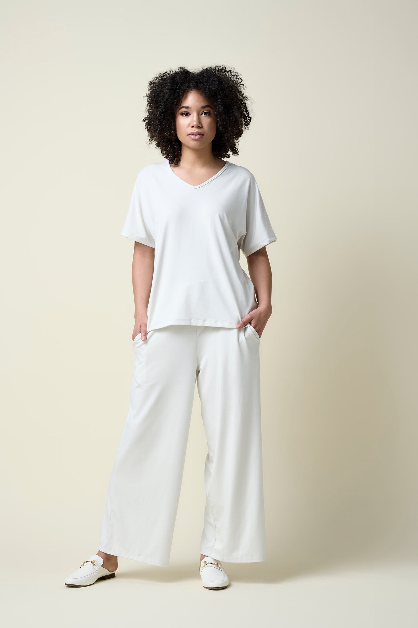 Woman wearing eggshell wide leg pants and matching v-neck t-shirt and loafers.