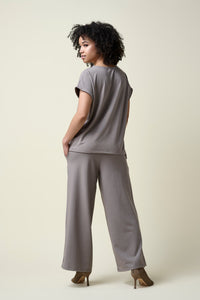 Back view of woman wearing stone coloured wide leg pants and matching t- shirt with heels.      