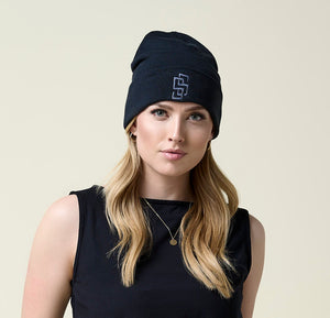 Close-up of woman wearing black beanie and black tank top.
